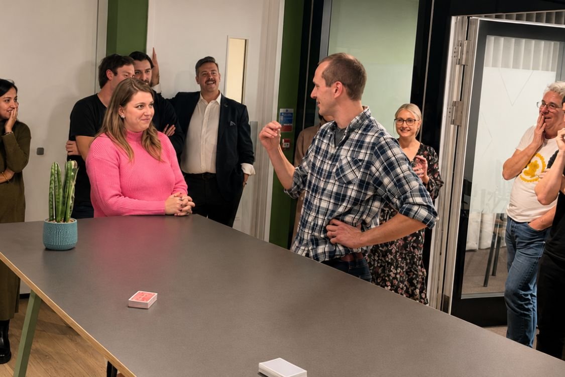 A corporate team gathered around a performer at a team building session