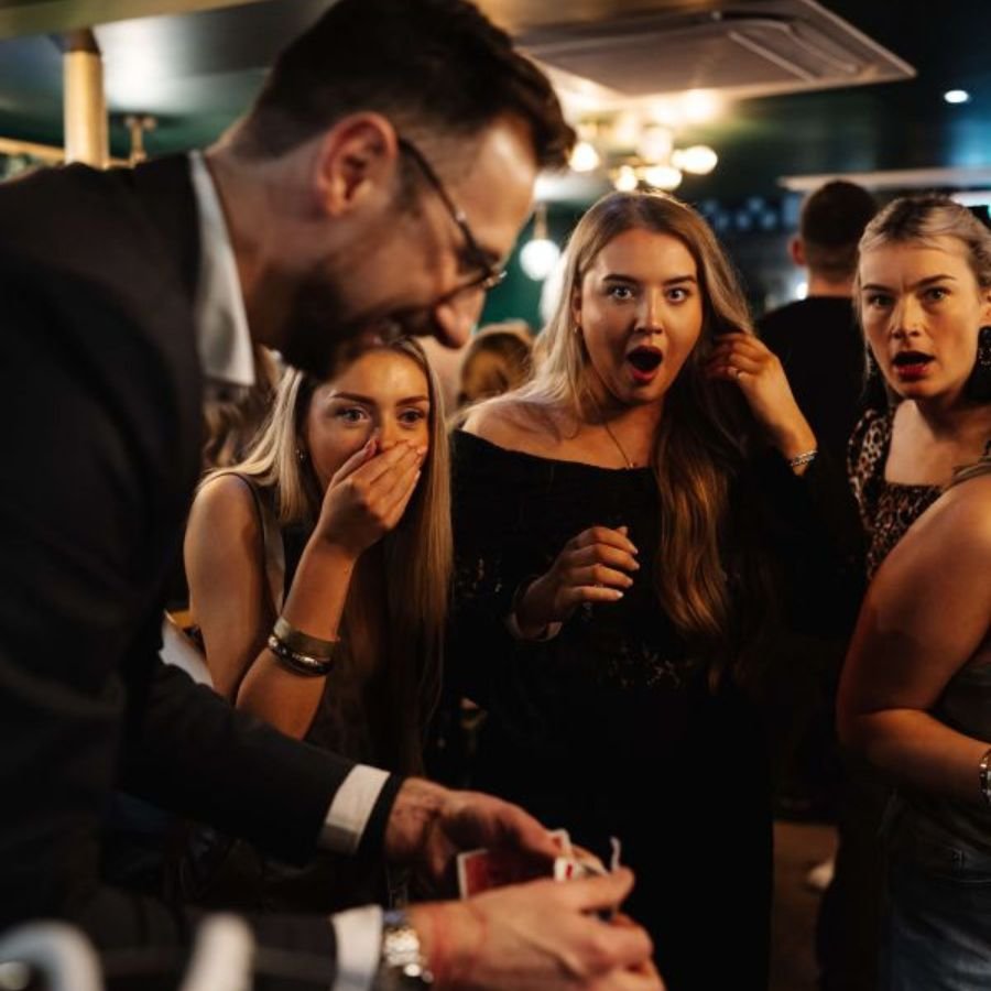A mix and mingle magician performing close-up magic for guests at a drinks reception
